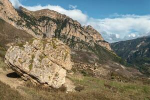 Riese balancieren Felsbrocken Felsen. schön Berg Landschaft mit Riese Granit Stein unter auf Hügel und Berge. bunt Hochland Landschaft mit groß Felsen unter Grün Vegetation und Berge. foto