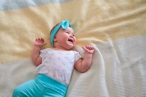 das Baby ist 6 Monate alt und Lügen auf das Bett und lächelt. ein schön Stirnband zum ein Baby. Kopieren Raum. foto