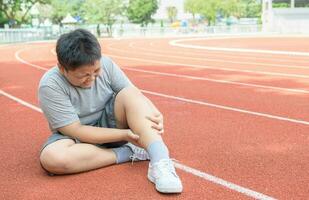 asiatisch Fett Junge halten seine Sport Bein Verletzung. Muskel schmerzlich foto