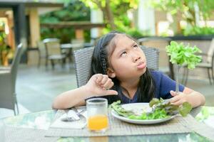 Mädchen mit Ausdruck von der Ekel gegen Gemüse foto