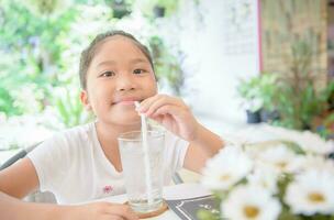 cate asiatisch Mädchen Trinken Glas von Wasser mit Eis foto