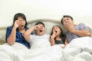 Vater und Mutter mit Kinder Gähnen und Dehnen im Bett, foto