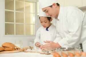 jung asiatisch Vater und seine Sohn tragen Koch Uniform Backen zusammen im Küche beim Zuhause foto