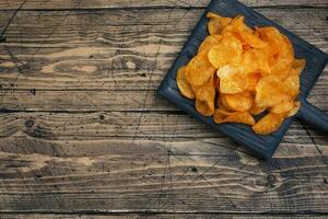 knusprig Kartoffel Chips, hölzern Hintergrund Textur von golden Chips. schnell Essen Snack. Kopieren Raum foto