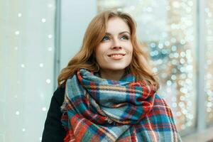 Süss Frau mit ein Lächeln im ein schön stilvoll Schal auf das Hintergrund von Beleuchtung foto