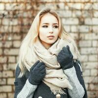 schön süß Mädchen mit ein warm Schal auf das Hintergrund von Backstein Mauer foto