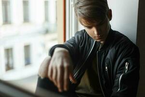 gut aussehend jung Mann Modell- sitzt auf das Fenster foto