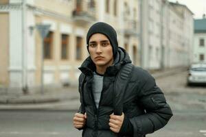 gut aussehend jung Mann im Winter Jacke und gestrickt schwarz Hut auf Stadt Hintergrund foto