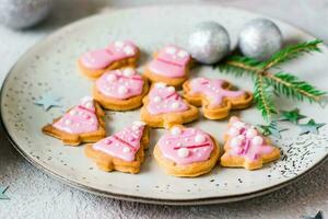 Weihnachten Kekse mit Rosa Glasur im ein Teller auf das Tisch. festlich behandeln. Nahansicht foto