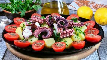 Cervia, Ravenna Provinz, Italien April 18, 2023. Tintenfisch Salat mit Kartoffeln ist ein traditionell Gericht bekannt alle Über das Welt. das Zusatz von Kirsche Tomaten und Rucola gibt Frische und Farbe. foto