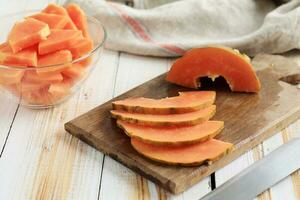 dünn Scheibe Papaya auf hölzern Tisch, gewürfelt Papaya auf Schüssel. foto