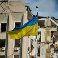 Flagge von Ukraine gegen das Hintergrund von ein zerstört Gebäude im Ukraine foto