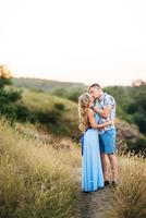 blondes Mädchen mit losen Haaren in einem hellblauen Kleid und einem Mann im Licht des Sonnenuntergangs foto