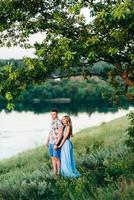 blondes Mädchen mit losen Haaren in einem hellblauen Kleid und einem Mann im Licht des Sonnenuntergangs foto