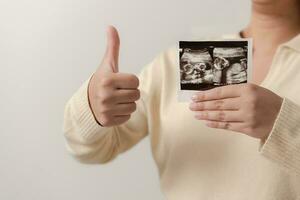 schwanger Frau halten Ultraschall Film von ihr Baby. glücklich Mutter und Neugeborene Baby im Verfahren. Liebe von Eltern zu Säugling im wenige Monate Vor geben Geburt. foto