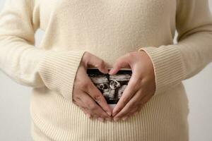 schwanger Frau halten Ultraschall Film von ihr Baby. glücklich Mutter und Neugeborene Baby im Verfahren. Liebe von Eltern zu Säugling im wenige Monate Vor geben Geburt. foto