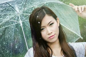 schön Mädchen ist Stehen mit Regenschirm unter ein Regen 4 foto