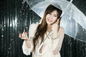 glücklich Mädchen halten transparent Regenschirm unter das Regen foto