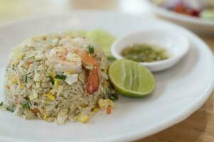 Garnele gebraten Reis auf ein Weiß Teller mit Fisch Soße Chili im ein Tasse foto