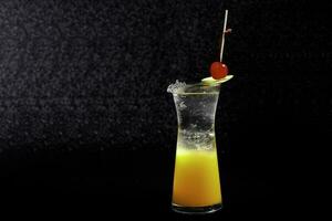 Cocktail mit Zitrone und Kirsche auf ein schwarz Hintergrund foto