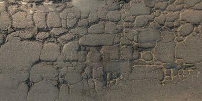 oben Aussicht von Oberfläche von Asphalt Straße gemacht von klein Steine und Sand mit Risse foto