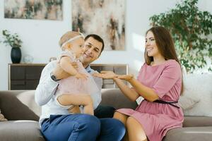 glücklich jung Familie mit einer Jahr alt Mädchen spielen im das Leben Zimmer von ihr Neu Zuhause foto