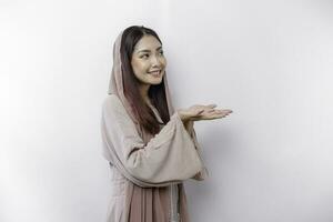 jung asiatisch Muslim Frau lächelnd während zeigen zu Kopieren Raum neben ihr foto