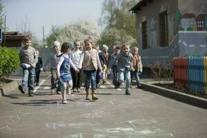 ein Gruppe von Kinder von Kindergarten auf ein gehen. foto