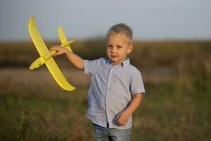 wenig Junge im das Feld Theaterstücke mit ein Flugzeug. foto