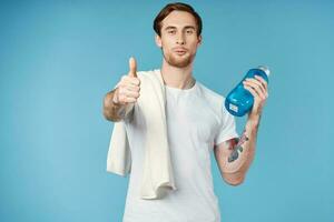 sportlich Mann mit Tätowierungen auf seine Waffen trinken Flasche Energie trainieren Blau Hintergrund foto