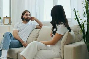 Mann und Frau freunde Sitzung auf das Couch und lächelnd fröhlich reden zu jeder andere haben ein gut Zeit zusammen. Lebensstil im Glück beim Zuhause foto