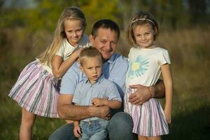 Papa mit Töchter und Sohn suchen in das Kamera. glücklich Vater und Kinder. foto