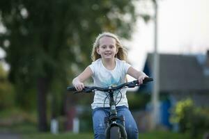 ein Mädchen mit lange Haar Fahrten ein Fahrrad auf ein Sommer- Tag. foto