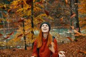 heiter Frau Reisen im das Herbst Wald im Natur in der Nähe von das Fluss und hoch Bäume im das Hintergrund foto