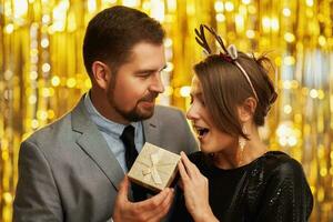 Paar mit Gold Geschenk auf Neu Jahr oder Weihnachten Party foto