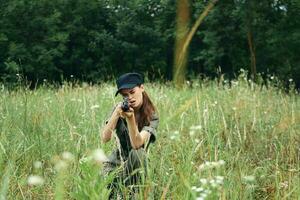 Frau mit Waffen im Hand sitzt auf das Boden auf Natur schwarz Deckel Grün foto