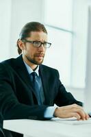 Geschäft Mann im ein passen mit Brille im das Büro beim seine Schreibtisch foto