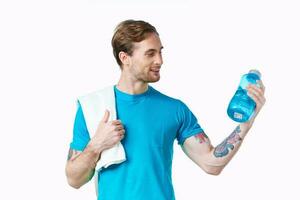 männlich Athlet im ein Blau T-Shirt mit ein trinken im ein Flasche und ein Handtuch auf seine Schulter foto