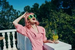 glamourös Frau im Rosa Kleid draußen mit Cocktail Trinken Alkohol foto