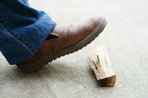 Nahansicht Mann trägt Schuhe ist Schritt auf rostig Metall Nagel auf Holz. Konzept, unsicher , Risiko zum gefährlich Tetanus. Sein Vorsichtig und aussehen um während Gehen beim Konstruktion Seite? ˅ oder Risiko setzt. foto