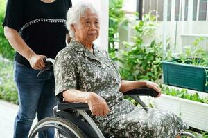 Pflegekraft Hilfe asiatisch Alten Frau Behinderung geduldig Sitzung auf Rollstuhl im Krankenhaus, medizinisch Konzept. foto