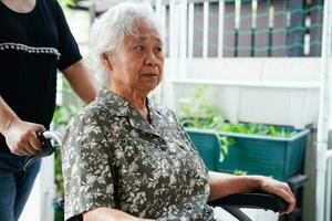 Pflegekraft Hilfe asiatisch Alten Frau Behinderung geduldig Sitzung auf Rollstuhl im Krankenhaus, medizinisch Konzept. foto