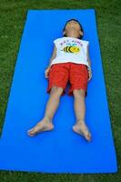 asiatisch Clever Kind tun Yoga Pose im das Gesellschaft Park draussen, Kinder- Yoga Pose. das wenig Junge tun Yoga und Meditation Übung. foto