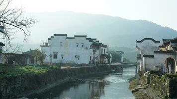 einer alt traditionell Chinesisch Dorf Aussicht mit das alt gewölbt Stein Brücke und alt hölzern Gebäude im das Süd- Landschaft von das China foto