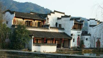 die schöne traditionelle chinesische dorfansicht mit der klassischen architektur und den frischen grünen bäumen als hintergrund foto