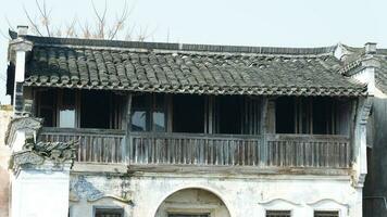 die schöne traditionelle chinesische dorfansicht mit der klassischen architektur und den frischen grünen bäumen als hintergrund foto