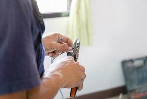 Elektriker schneidet elektrisch Drähte mit Zange, Techniker Installation Luft Konditionierung im ein Klient Haus, Handwerker Festsetzung Luft Conditioner Einheit, Instandhaltung und reparieren Konzepte foto