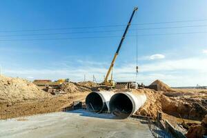 verbinden ein Graben ablassen zu ein Beton Mannloch Struktur beim Konstruktion Seite? ˅. Beton Stapel im Schalung Rahmen zum konstruieren Regenwasser und unter Tage Dienstprogramme, Pumpe Stationen, Kanalisation Rohre foto