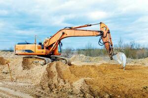 Bagger graben die Gräben auf einer Baustelle. Graben zum Verlegen von externen Abwasserrohren. Abwasserentsorgungssystem für ein mehrstöckiges Gebäude. Graben des Grubenfundaments foto