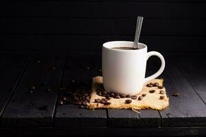 frisch gebraut Kaffee. Kaffee Tasse oder Becher vereinbart worden auf ein schwarz hölzern Tabelle mit geröstet Kaffee Bohnen. Espresso Mokka Cappuccino Barista auf dunkel Hintergrund. foto